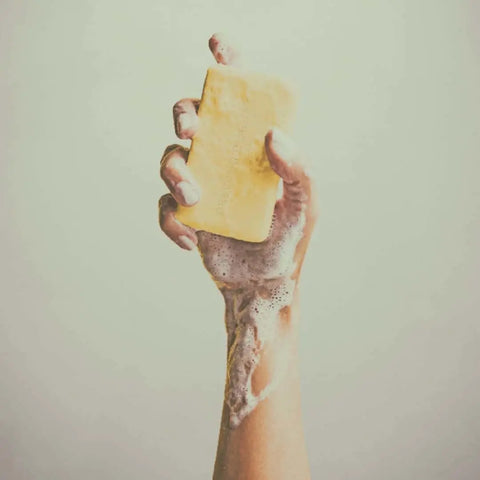 Hand holding a natural soap bar with foam on the arm, symbolizing cold processed soaps