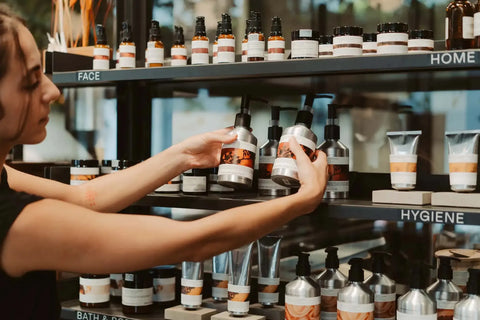 Woman reaching for skincare bottles on shelves, symbolizing essential daily routine steps