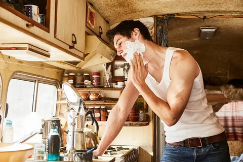 Man shaving in a rustic bathroom with natural light, symbolizing natural shaving tips