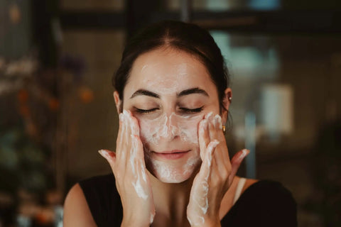 Smiling woman washing her face with cleanser, representing natural skincare