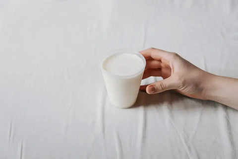 Hand holding a cup of milk, symbolizing balance with prebiotics and probiotics