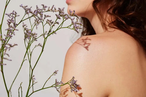 Woman’s bare back with flowers on shoulder, symbolizing radiant natural skin