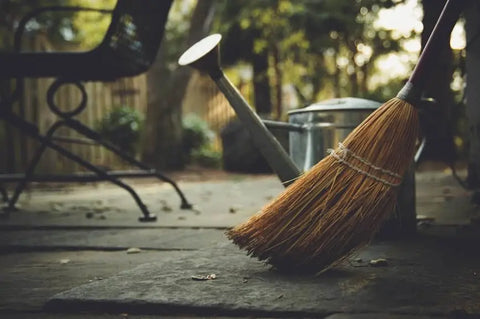 Broom sweeping outdoors in sunlight, symbolizing spring cleansing ritual