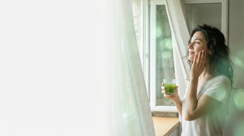 Minimalist floral arrangement featuring a red anthurium blossom and a tall green leaf in a shallow green bowl, representing Brewing Beauty's Depurate Skincare collection.